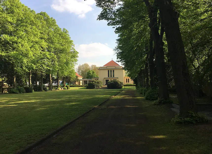 Weg zwischen Rasenflächen und Gehölzen auf dem Friedhofsgelände