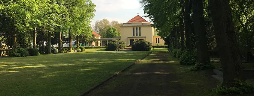 Gepflegte Grünanlage mit Rasenfläche und altem Baumbestand